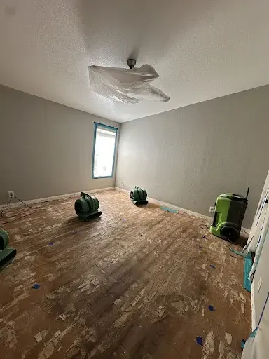 Air movers and a dehumidifier drying an opened floor in a Garden Grove bedroom