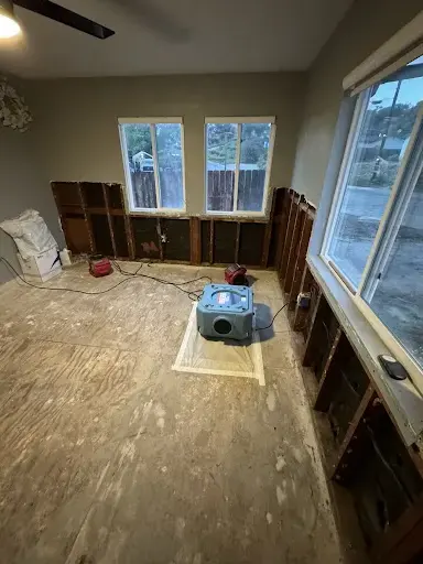Air mover set on an opened subfloor with baseboards removed in a Garden Grove home