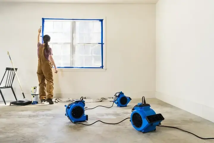 Air movers drying a room with the wall base prepped in Garden Grove