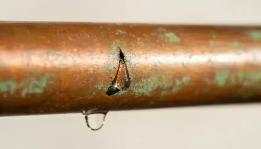 Pinhole in a corroded copper water line dripping water in a Garden Grove home