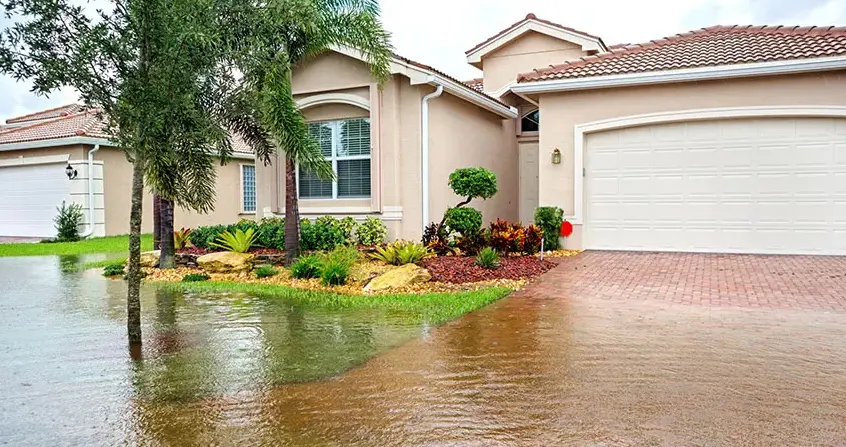 Storm water flooding the front yard and driveway of a stucco home in Garden Grove