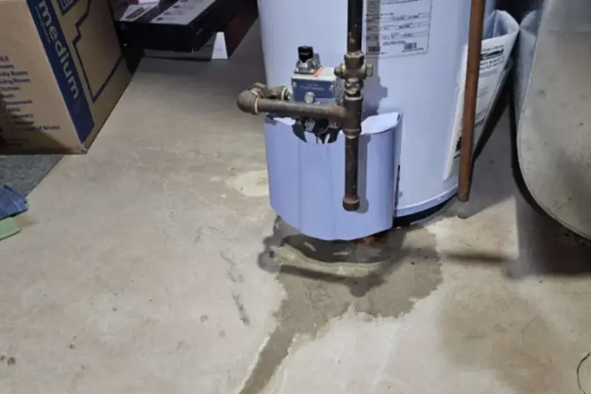 Water spreading across a concrete garage floor from a leaking water heater in Garden Grove